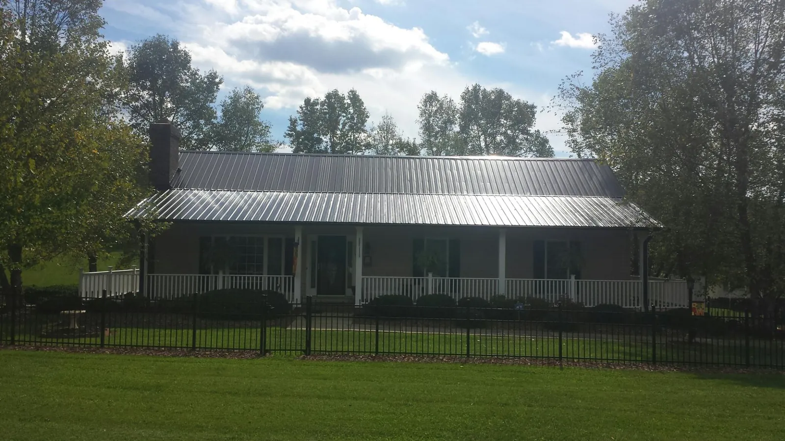 Gray metal roof on a brick ranch with a full width front porch — Gutter Guard Installation work by our crew in Huntington Beach