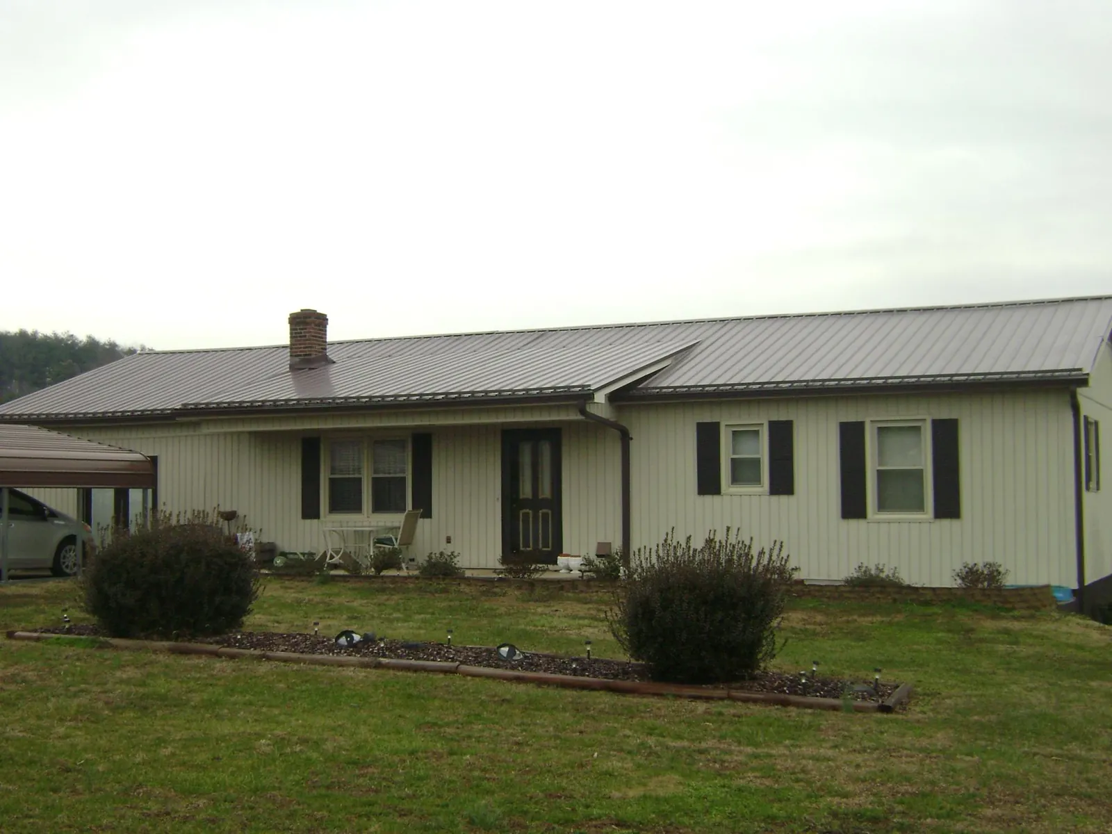 Brown metal roof on a cream sided ranch home with a brick chimney in Huntington Beach