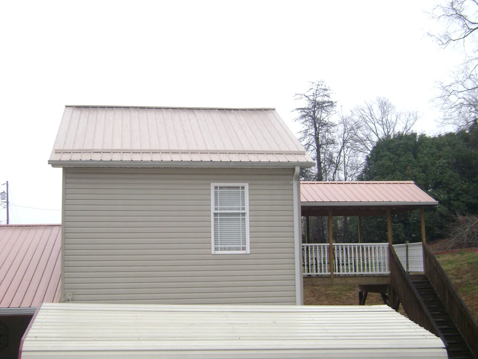 Tan metal roofs on a two story addition and attached porch, from a Roof Replacement job in Huntington Beach