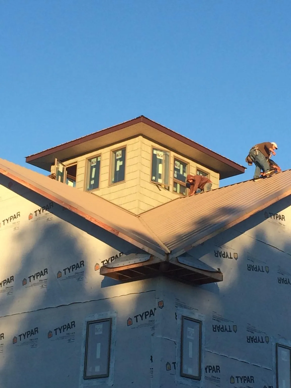 Roofers working around a rooftop cupola on a new metal roof at sunset — Roof Waterproofing in Huntington Beach by Roofing Brothers